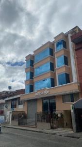 ein Hotelgebäude mit blauen Fenstern auf einer Straße in der Unterkunft HOTEL 4 RIOS in Cuenca
