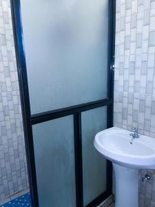 a bathroom with a sink and a glass shower at Ruaka studio Airbnb in Ruaka