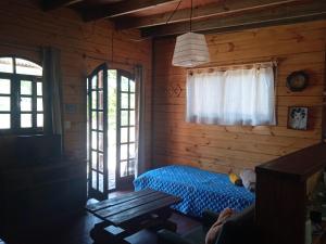1 dormitorio con 1 cama en una cabaña de madera en Cabaña La Federica, en La Paloma