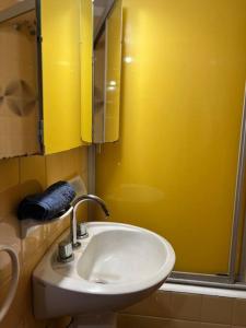 Baño amarillo con lavabo y espejo en 2 ambientes para 4 personas en Mar del Plata