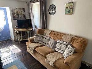 ein Wohnzimmer mit einem braunen Sofa mit Kissen darauf in der Unterkunft Tardoire cottage in Oradour-sur-Vayres