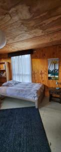 a bed in a wooden room with a window at Casa del río in Cochrane