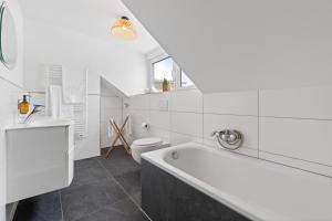ein weißes Bad mit einer Badewanne und einem WC in der Unterkunft Casa Verde: Küche, TV, Nespresso, im Grünen in Starnberg
