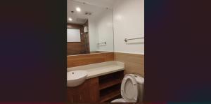a bathroom with a toilet and a sink and a mirror at Cozy Suite Studio type condo in Matina Enclaves in Davao City