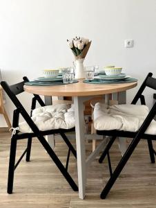 uma mesa de madeira com duas cadeiras e um vaso com flores em Casa da Ana - Country Home em Terrugem