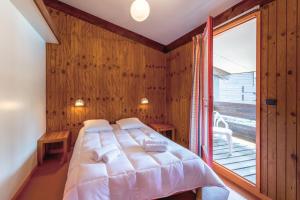 ein Schlafzimmer mit einem Bett und einem großen Fenster in der Unterkunft Résidence les Sentes in Carcans