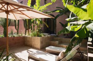 Maison Brummell Majorelle في مراكش: فناء مع طاولة ومظلة والدرج