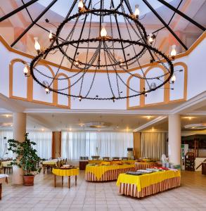 un grand hall avec des tables jaunes et un grand lustre dans l'établissement Club Hotel Gultur, à Küçükkuyu