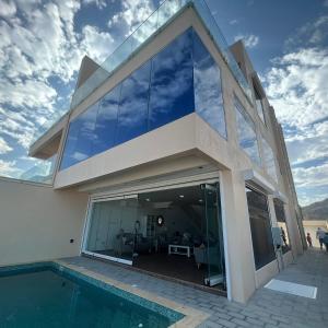 a house with glass windows and a swimming pool at Casa Del Mar Villa in As Sīfah
