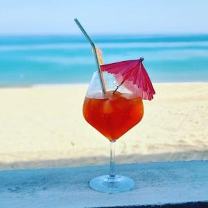 uma bebida num copo sentado numa mesa perto da praia em Casa Del Mar Villa em As Sifah