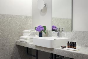 ein Badezimmer mit einem Waschbecken, einem Spiegel und Handtüchern in der Unterkunft Classik Hotel Alexander Plaza in Berlin