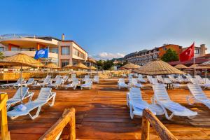 een groep ligstoelen en parasols op een houten terras bij Club Hotel Gultur in Kucukkuyu