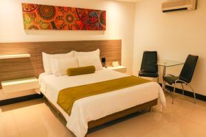 1 Schlafzimmer mit einem großen Bett und 2 Stühlen in der Unterkunft Hotel Loyds in Medellín