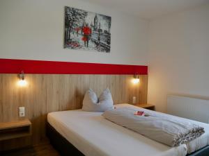 a bedroom with a white bed with a red stripe on the wall at Hotel Hohenloher Tor in Bretzfeld