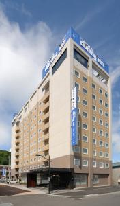 ein großes Hotelgebäude mit blauem Schild drauf in der Unterkunft Dormy Inn Wakkanai in Wakkanai