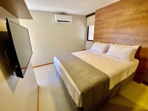 um quarto com uma cama e uma televisão de ecrã plano em Edifício Top Unique ER Hospedagens em Maceió