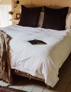 a large white bed with a book on it at No 24 Beverston Castle in Tetbury