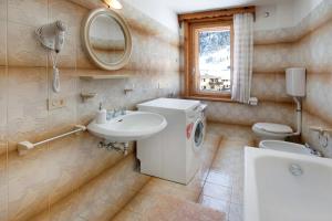 ein Badezimmer mit einem Waschbecken, einem WC und einem Spiegel in der Unterkunft Appartamento La Tesciadra in Livigno