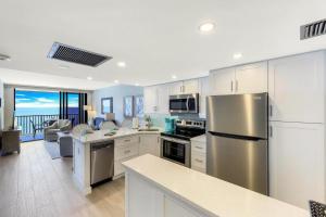a kitchen with a stainless steel refrigerator and a living room at Charming beachfront condo with pool, spa and views in Marco Island