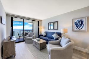 a living room with a blue couch and chairs at Charming beachfront condo with pool, spa and views in Marco Island