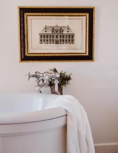 a picture of a house on a wall above a bath tub at No 24 Beverston Castle in Tetbury