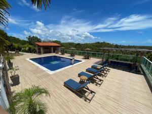 a deck with lounge chairs and a swimming pool at Chalés Alto dos Milagres in São Miguel dos Milagres