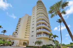 a tall white apartment building with palm trees at Sandcastle I-1201 in Marco Island