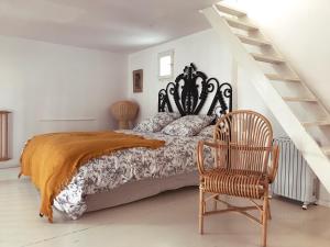 a bedroom with a bed and a chair and stairs at La Maison Jasmin in Arles