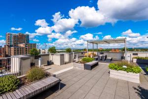 a rooftop patio with benches and plants on a building at Hilltop Serviced Apartments - Ancoats in Manchester