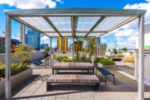 a rooftop patio with benches and a canopy at Hilltop Serviced Apartments - Ancoats in Manchester