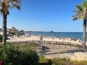 una spiaggia con sedie e ombrelloni e l'oceano di Apartment in Mar Menor Golf Resort a Torre-Pacheco