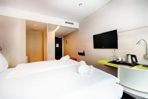 a hotel room with two beds and a flat screen tv at B&B Hotel Aalen in Aalen