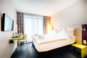 una camera d'albergo con un grande letto e una scrivania di B&B Hotel Aalen ad Aalen