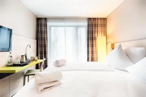 una habitación de hotel con una gran cama blanca y una ventana en B&B Hotel Aalen, en Aalen