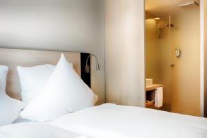 a bedroom with a white bed and a mirror at B&B Hotel Aalen in Aalen