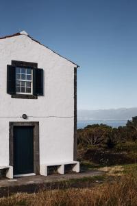 ein weißes Gebäude mit einer grünen Tür und einem Fenster in der Unterkunft Liiiving in Açores - Ocean View House in Canto da Areia