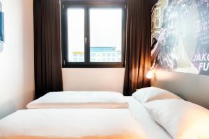 Duas camas num pequeno quarto com uma janela em B&B Hotel Augsburg-West em Augsburg