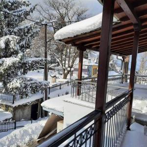 a porch covered in snow with a wooden railing at Ilenia Guesthouse in Zagora