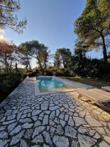 een stenen loopbrug met een zwembad in een achtertuin bij Le Mazet - Petit paradis Nîmois in Nîmes