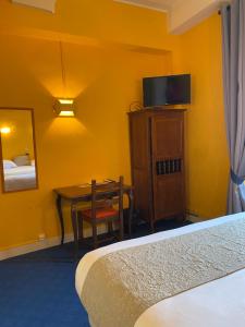 a hotel room with a bed and a table and a television at Hostellerie Du Chateau in Châteauneuf