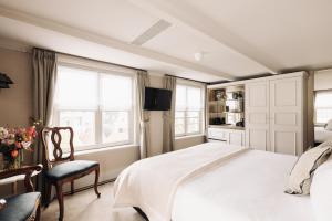 a bedroom with a bed and a chair and windows at Hotel 717 in Amsterdam