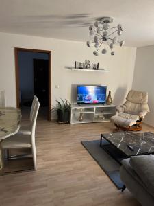 ein Wohnzimmer mit einem TV, einem Tisch und Stühlen in der Unterkunft Ferienwohnung Schwarzwald in Pforzheim