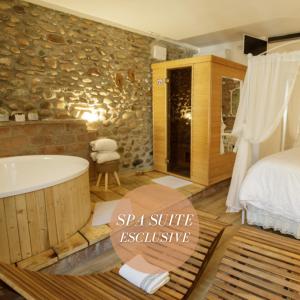 un bagno con vasca e una camera da letto con parete in pietra di GardaBeds Adults Only a Castelnuovo del Garda