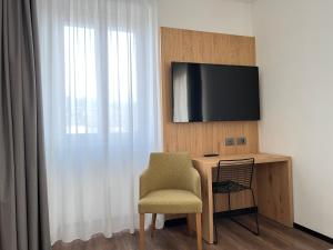 Habitación con escritorio con silla y TV. en Hotel Belvedere en Spiazzi Di Caprino