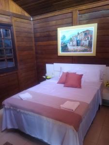 - une chambre avec un grand lit blanc et des oreillers rouges dans l'établissement Farol House, à Maricá
