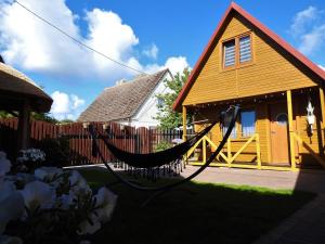 a hammock in front of a yellow house at Domki u Skrzata Drewniane in Łeba