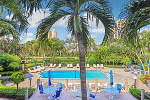 une piscine de villégiature avec des chaises et un palmier dans l'établissement Idyllic inland condo with pool and beach access, à Marco Island