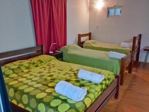 a room with three beds with green and yellow sheets at La Casita in La Banda