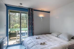 una camera da letto con un letto grande e un balcone di Résidence les Cavales a Carcans