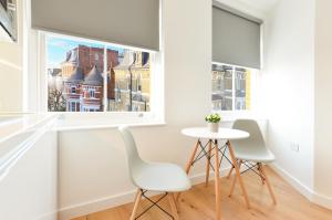 uma sala de jantar com uma mesa e 2 cadeiras e uma janela em West Hampstead Serviced Apartments by Concept Apartments em Londres